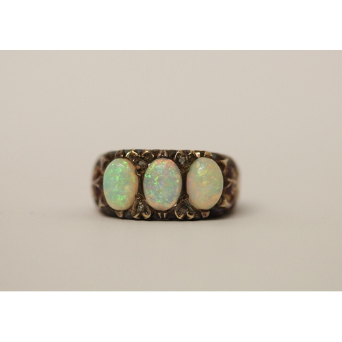 573 - An opal three stone and diamond ring, three large opals with good play of colour in 9ct gold setting... 