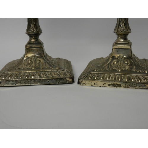 500 - A pair of square based silver candlesticks, with embossed decoration, fixed sconces,  Sheffield 1901... 