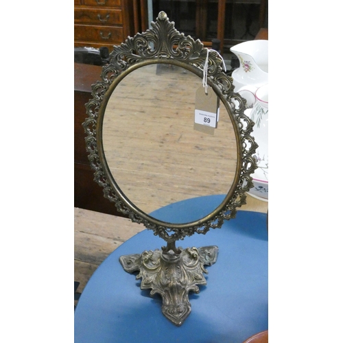 89 - A decorative oval brass framed free standing mirror