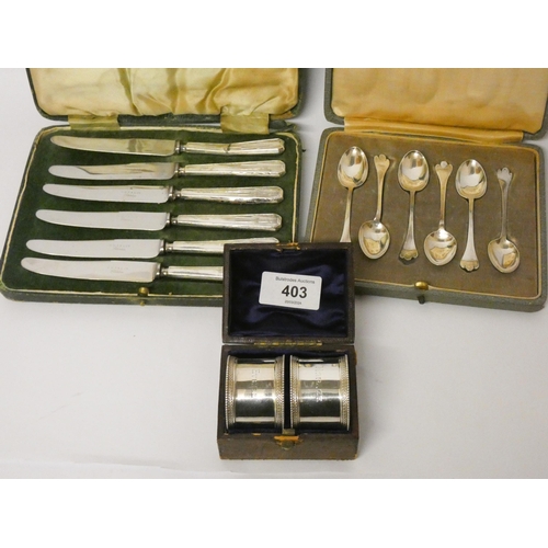 403 - A pair of silver napkin rings in fitted box, engraved, with a set of six trefid pattern coffee spoon... 