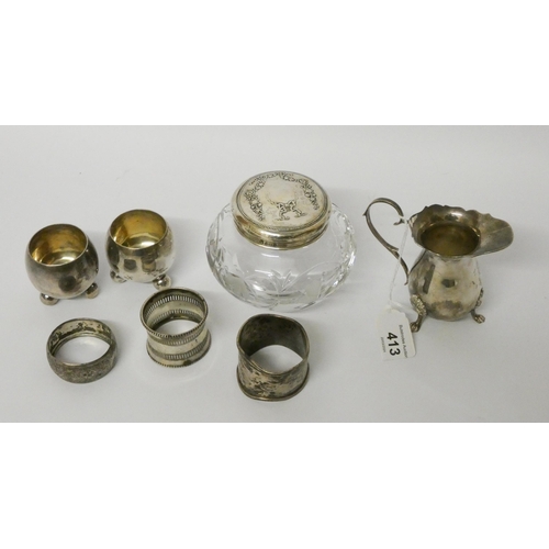 413 - Small silver ware to include a cream jug, three napkin rings, pair of salt cellars and a silver topp... 