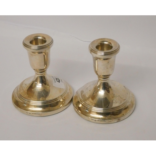 425 - A pair of silver circular based candlesticks, weighted, 11 cms high