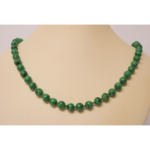 436 - A long uniform row of malachite beads, knotted silk, to yellow metal clasp, 70 cms long.