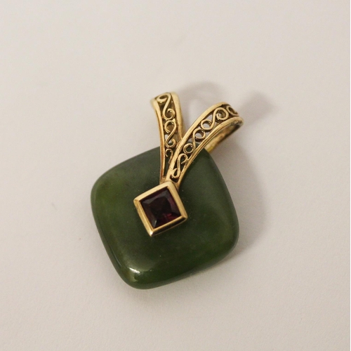 498 - A carved jade pendant with a central garnet with 9ct gold suspension loop