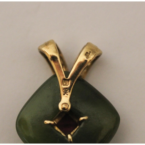 498 - A carved jade pendant with a central garnet with 9ct gold suspension loop