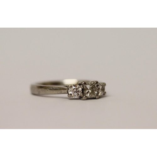 502 - A three stone diamond ring, with a princess cut diamond to the centre, on platinum band, ring size K... 