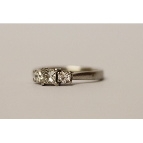 502 - A three stone diamond ring, with a princess cut diamond to the centre, on platinum band, ring size K... 