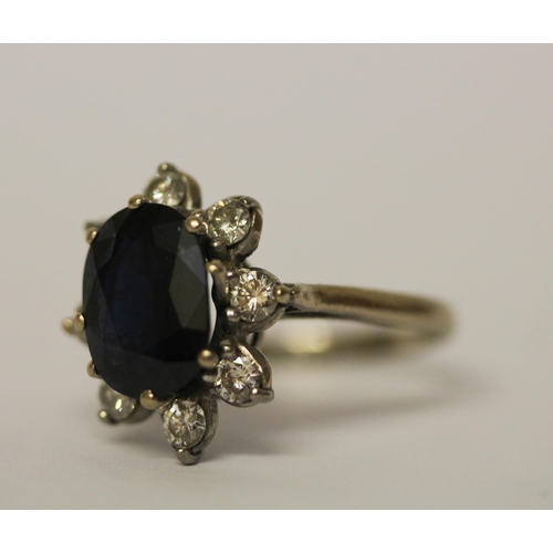 514 - A large sapphire and diamond cluster ring, the large oval sapphire surrounded by eight brilliant cut... 