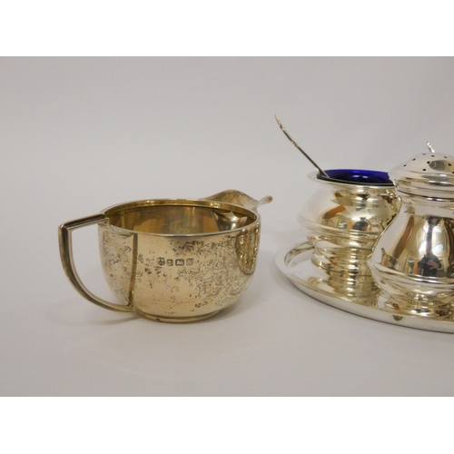 431 - A modern three piece silver cruet set, with spoons, blue glass liners and circular plated stand and ... 