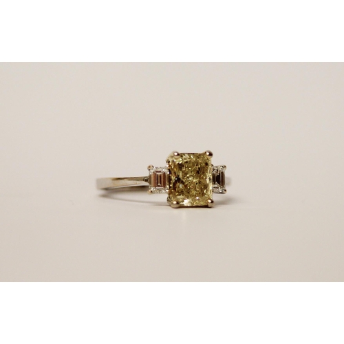 534 - A yellow and white three stone diamond ring, the central radiant cut fancy intense yellow diamond we... 