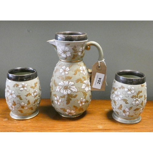 204 - A stoneware lemonade jug with silver plated rim and a pair of matching beakers