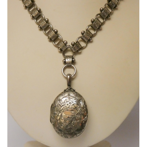 499 - A Victorian silver oval locket engraved with scroll and foliage on a wide engraved fancy link chain,... 