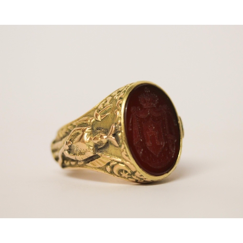 526 - A large gents intaglio panel ring, the oval hardstone panel carved with heraldic motif, on 14ct yell... 