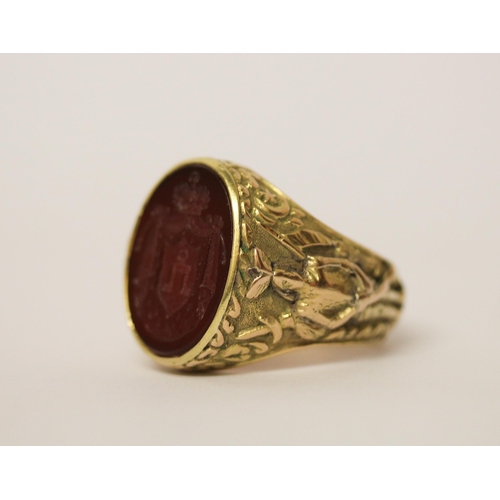 526 - A large gents intaglio panel ring, the oval hardstone panel carved with heraldic motif, on 14ct yell... 