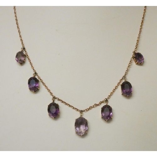 550 - An Edwardian amethyst fringe dropper necklace, set with seven claw set oval amethysts on 9ct rose go... 