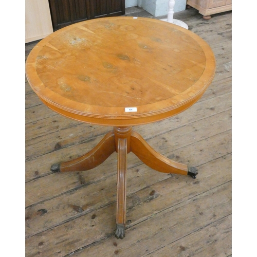 64 - A small circular yew wood dining table on pillar base with bras feet