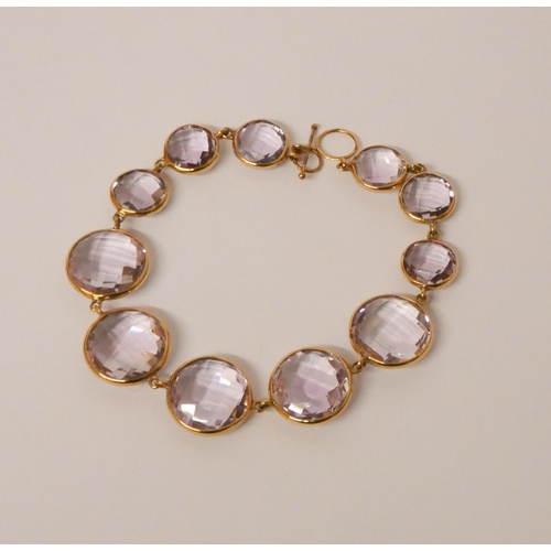 576 - Rhapsody faceted amethyst circular panel bracelet mounted in 9ct gold.