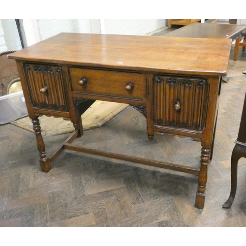 136 - A reproduction oak kneehole dressing table or desk fitted drawer and two linen fold panel cupboards,... 