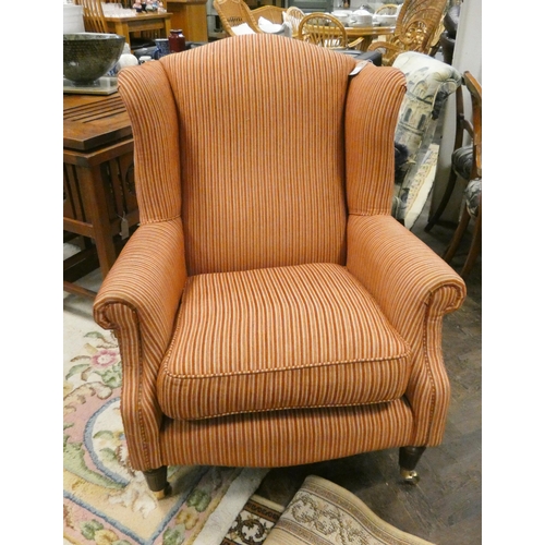 139 - A wing backed easy chair in orange striped material