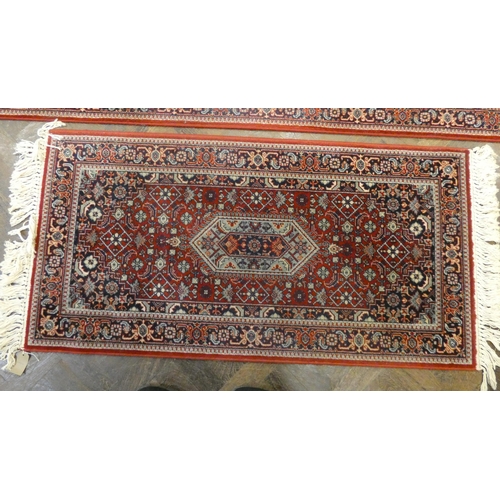 160 - A large red and patterned Wilton style rug, matching hall runner and one other smaller matching rug ... 