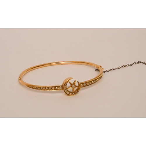 529 - An Edwardian seed pearl hinged bangle, the centre with star and crescent motif, set graduated seed p... 