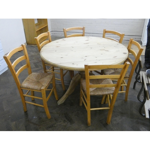 43 - A circular Deal top dining table and a set of six ladder back style beech dining chairs with rush se... 