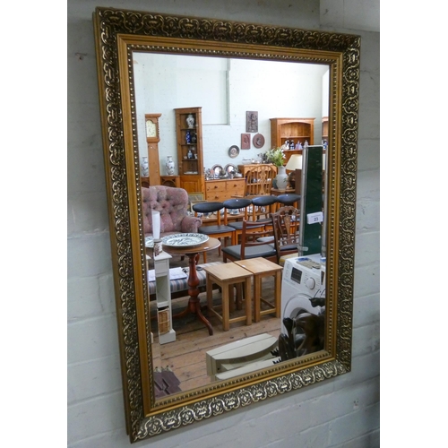 23 - A bevelled wall mirror in decorative gilt frame