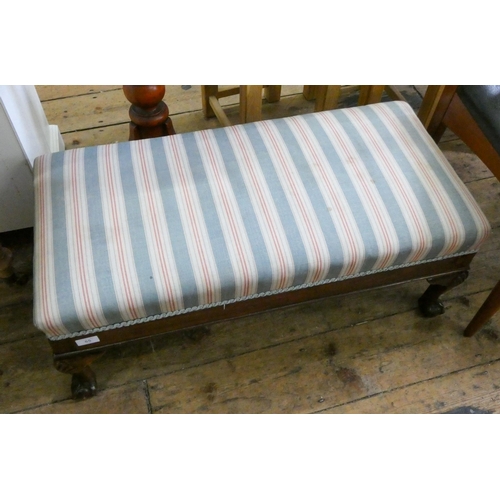 65 - A long upholstered footstool standing on claw and ball feet