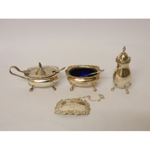 533 - A three piece hallmarked silver cruet set with blue glass liners and spoons and a brandy decanter la... 