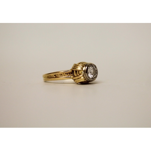 597 - A modern solitaire diamond ring, in a rub over circular setting on 18ct yellow band. Marked 18ct. Ri... 