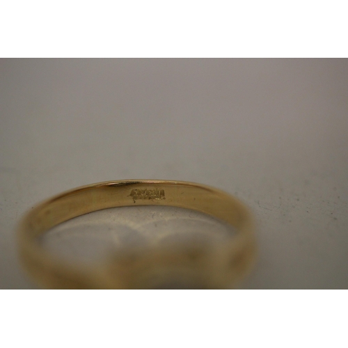 597 - A modern solitaire diamond ring, in a rub over circular setting on 18ct yellow band. Marked 18ct. Ri... 