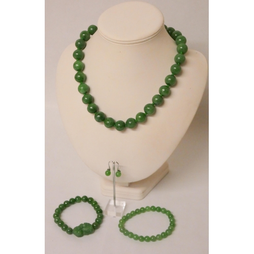 588 - A green jade bead necklace with magnetic clasp, a pair of ear studs and two matching jade bead brace... 