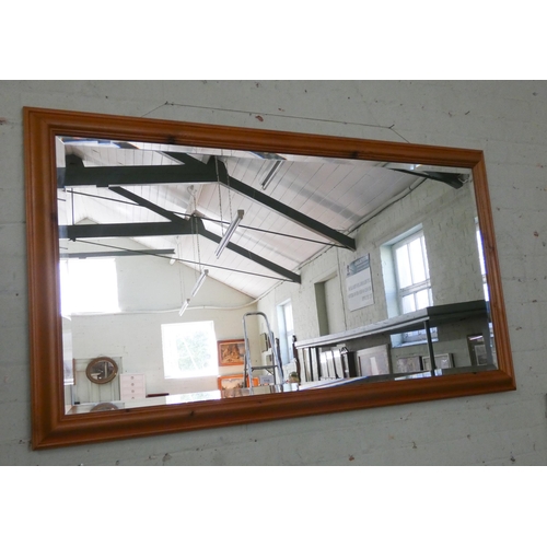 110 - A large bevelled wall mirror in pine frame