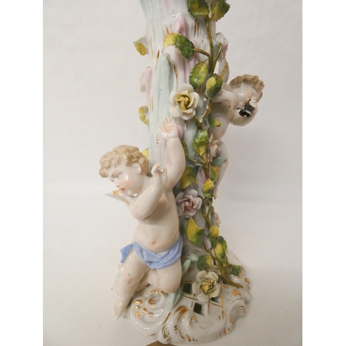 218 - A German floral encrusted porcelain cherub mounted candlestick base. Blue cross sword mark to the ba... 