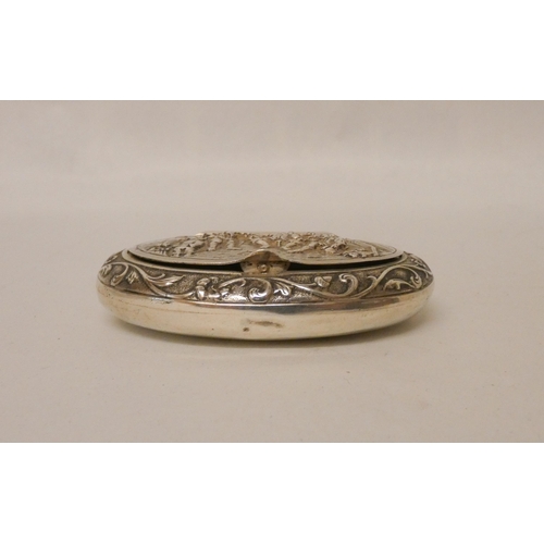 553 - A oval continental silver patch or snuff box, the hinged lid decorated with merry-making scene. Impo... 