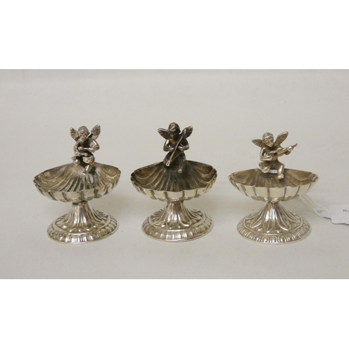 564 - Three matching sterling silver shell shaped salt cellars with cherub mounts. Marked 925 to base. 3.6... 