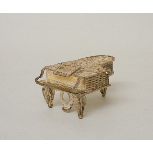 576 - A miniature silver filigree trinket box in the form of a grand piano. 5cm across.