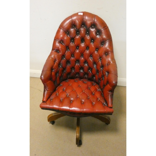 350 - A revolving office elbow chair in buttoned red leather.