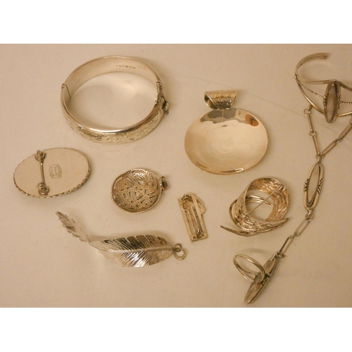 606 - A silver hinged bangle, various silver pendants, hand jewellery and brooches.