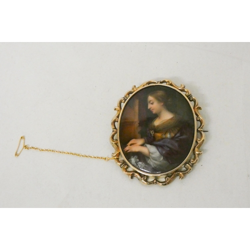 642 - A 19th Century gold mounted oval porcelain brooch, painted as a portrait of a lady playing the piano... 