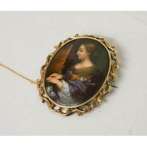 642 - A 19th Century gold mounted oval porcelain brooch, painted as a portrait of a lady playing the piano... 