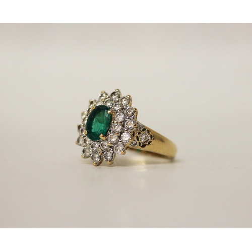 680 - An emerald and diamond oval cluster ring. The claw set emerald surrounded by two rows of brilliant c... 