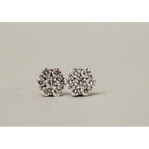 676 - A pair of platinum and diamond ear studs set in a diamond daisy design in platinum with safety screw... 