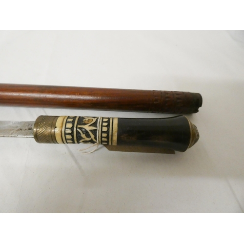 761 - An Indian sword stick in hardwood cane, ebonised handle with brass pommel. Blade measures approx 2' ... 