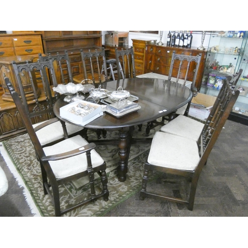 56 - An Ercol oak extending dining table with fold away centre leaf together with eight matching spindle ... 