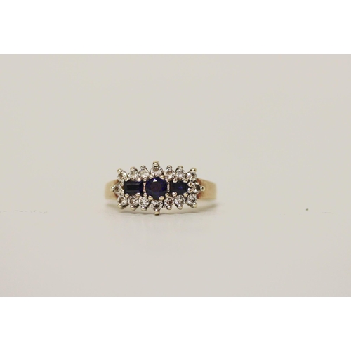 665 - A three stone sapphire and diamond cluster panel ring, on hallmarked 9ct yellow gold band. Ring size... 