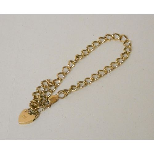 695 - A curb link 9ct yellow gold bracelet with heart shaped padlock fastening and safety chain. Gross wei... 