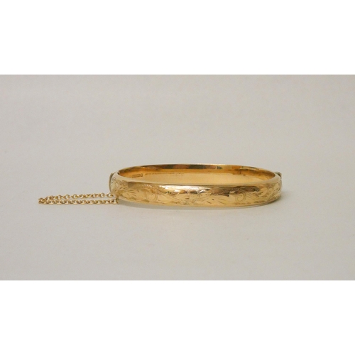 716 - A 9ct yellow gold ladies hinged bangle with all over engraved decoration, hallmarked, invisible clas... 