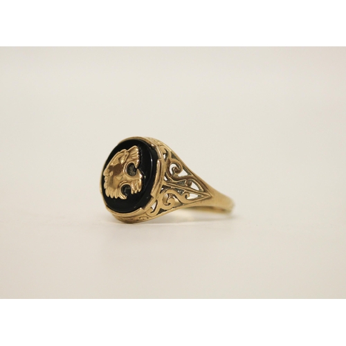 728 - A gents signet ring, the onyx panel with overlaid gold roaring lion motif, on pierced 9ct yellow gol... 