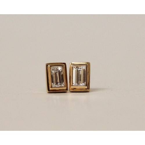 731 - A pair of diamond ear studs, each set with an emerald cut diamond in rectangular collet setting to s... 